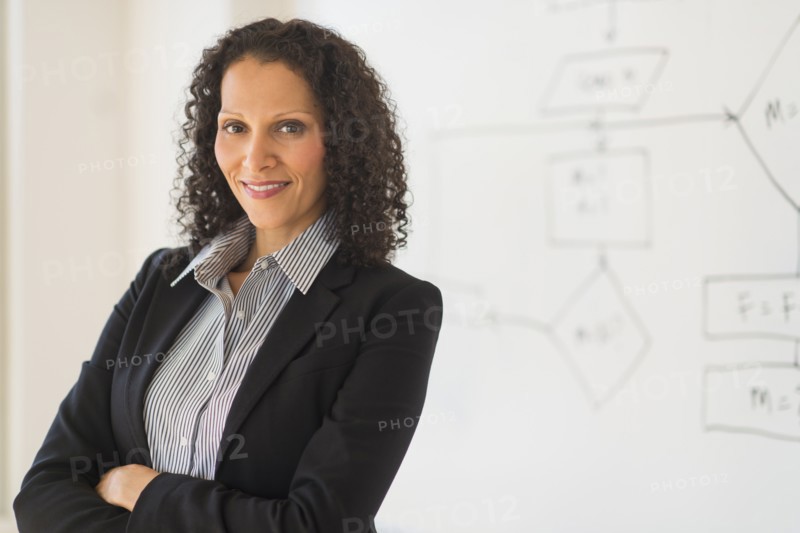 Portrait of woman standing next to whiteboard.