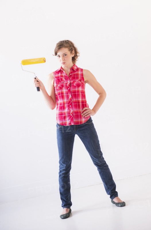 Studio shot of young woman holding paint roller. Photo: Daniel Grill