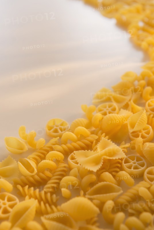 Variety of yellow pasta with blank white space in upper left corner. Photo : Daniel Grill