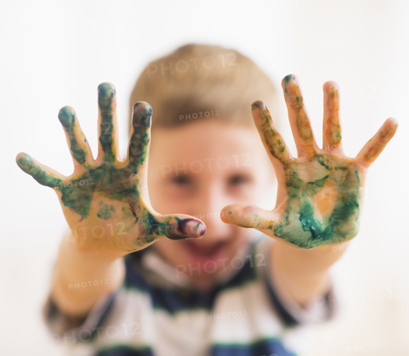Young boy (6-7) showing hands stained with paint. Photo : Daniel Grill