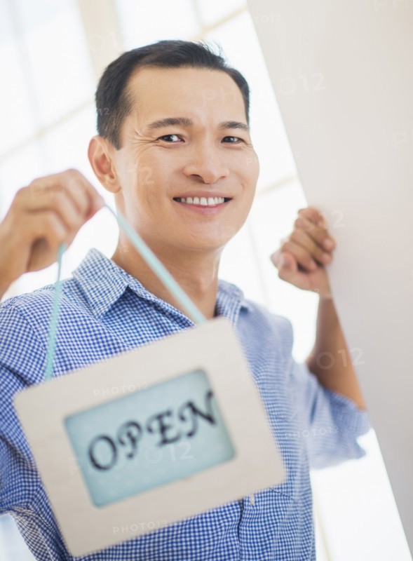 Mid adult man holding open sign. Photo: Daniel Grill