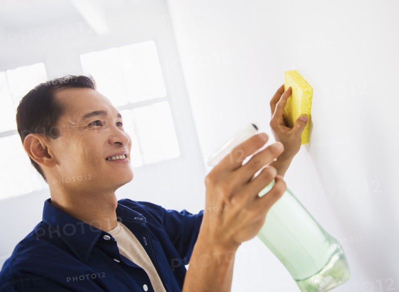 Man washing white walls with spray and yellow sponge. Photo: Daniel Grill