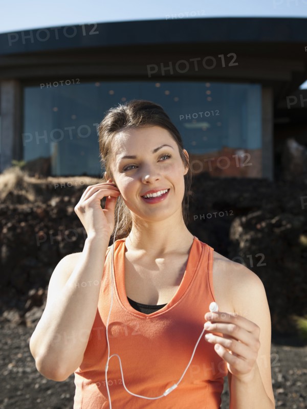 Young attractive woman plugging earphones in her ears. Photo: Erik Isakson