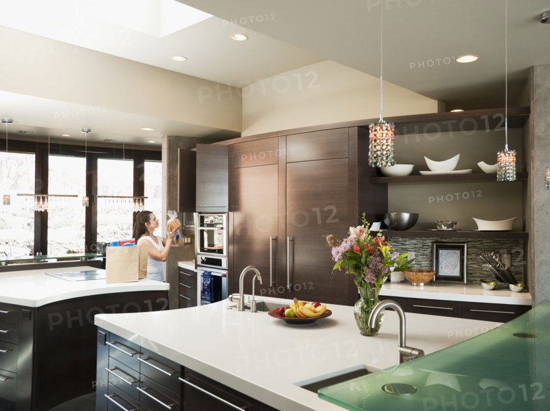 Young woman bustling around in modern domestic kitchen.