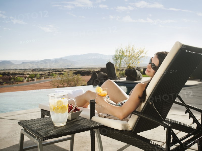 Young attractive woman enjoying cocktail by swimming pool.