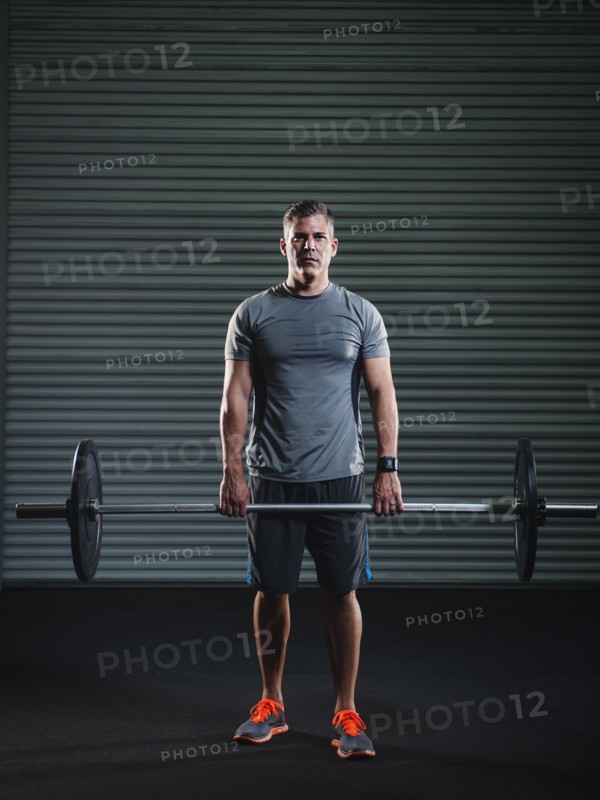 Mature man lifting heavy barbell .