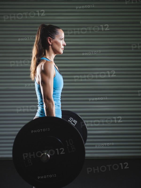 mid adult woman lifting barbell .