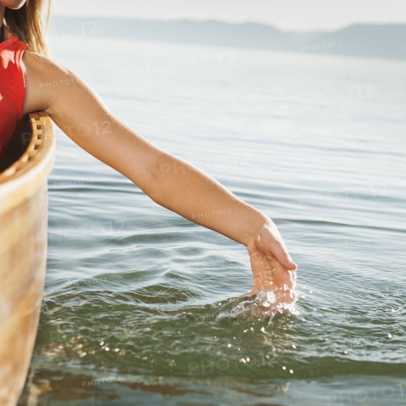 Young woman's hand splashing lake water. Photo: Erik Isakson