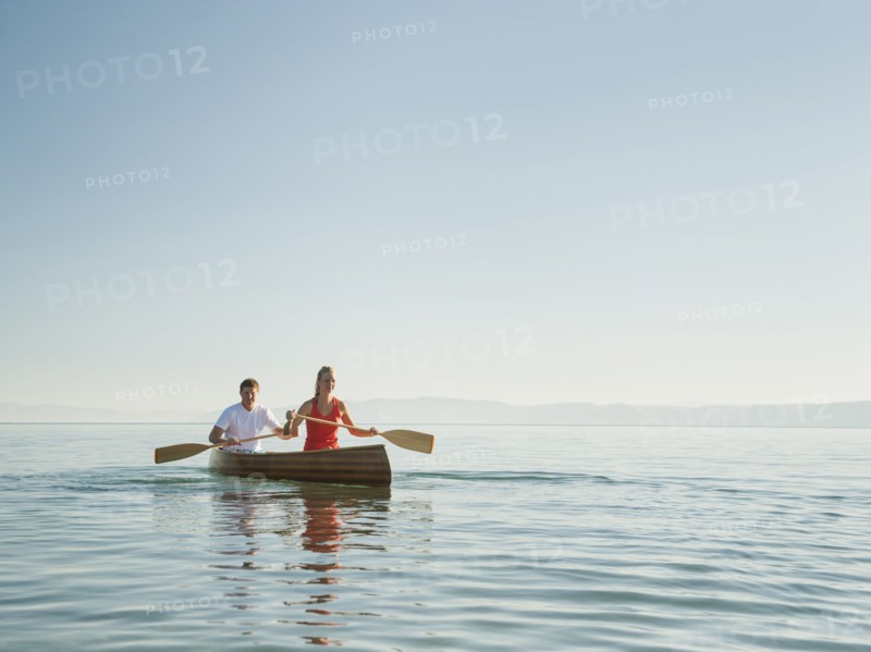 Portrait of two young people paddling canoe.