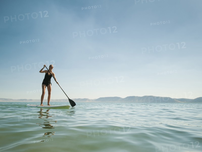 Young woman standing on paddleboard.
