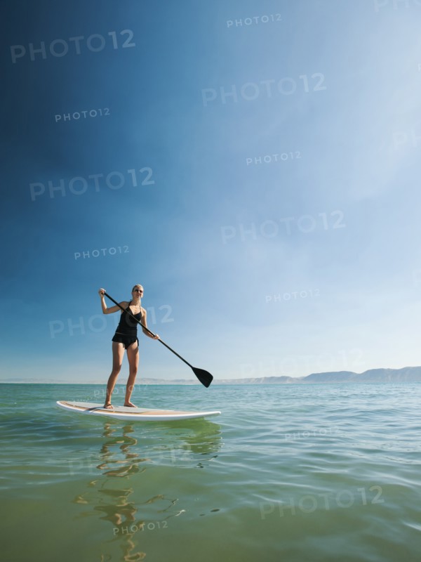 Young woman standing on paddleboard.