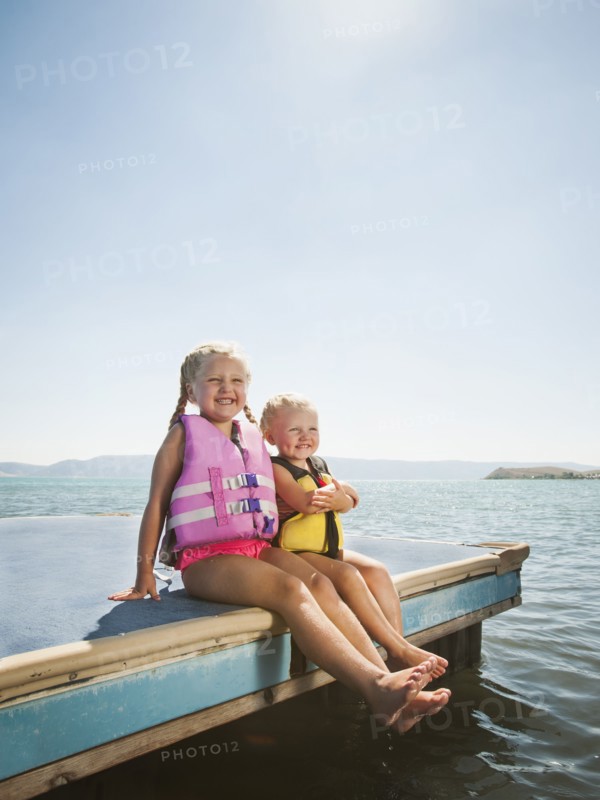 Girls (2-3, 4-5) sitting at the edge of raft in life jackets. Photo: Erik Isakson