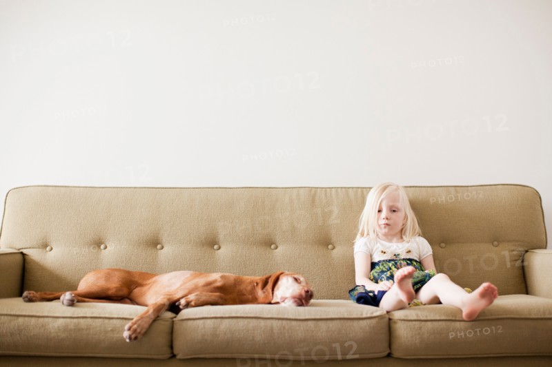 Girl (4-5 years) on couch with dog. Photo : Jessica Peterson