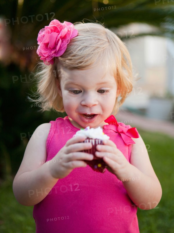 Girl with blong hair looking at cupcake. Photo : Jessica Peterson