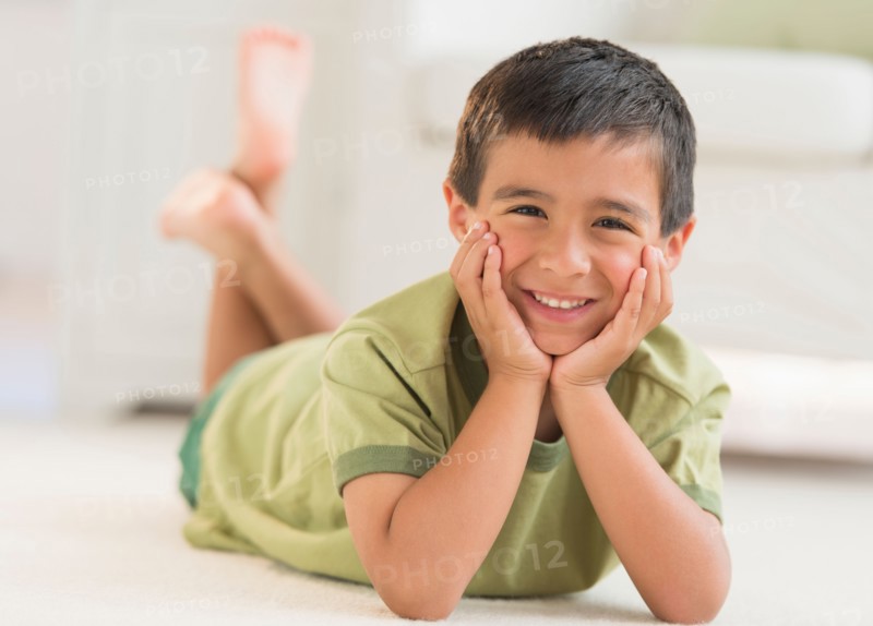 Portrait of boy (6-7) lying on carpet.
