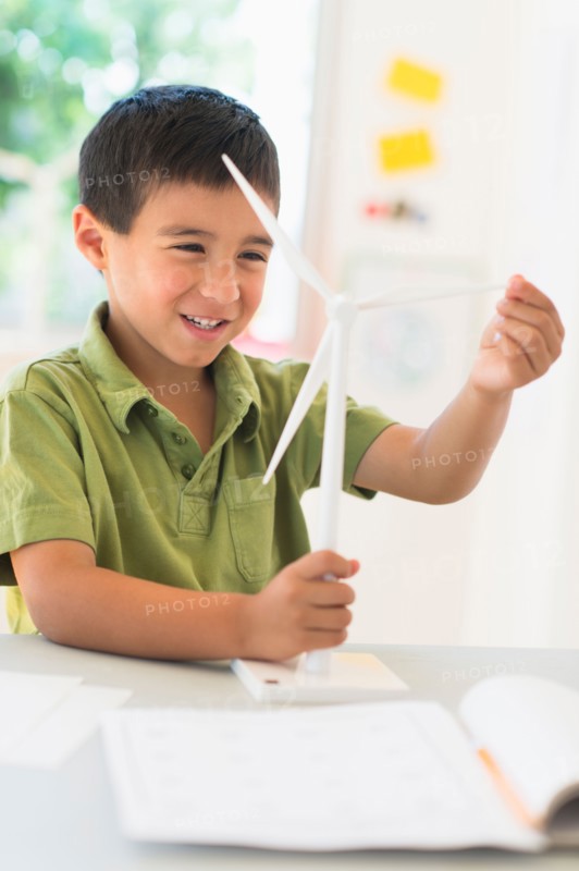 Boy (6-7) holding scale model of wind turbine.