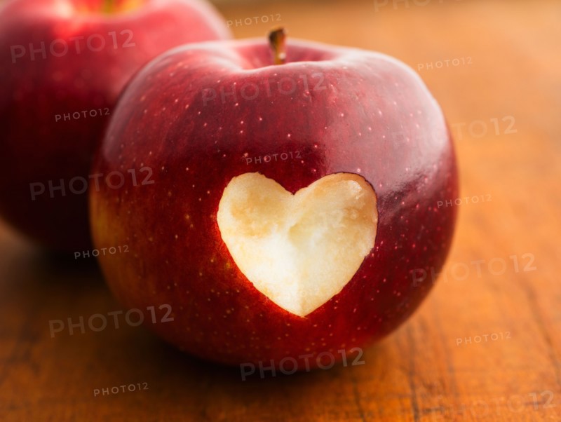 Close up of apple with missing bite in heart shape, studio shot.