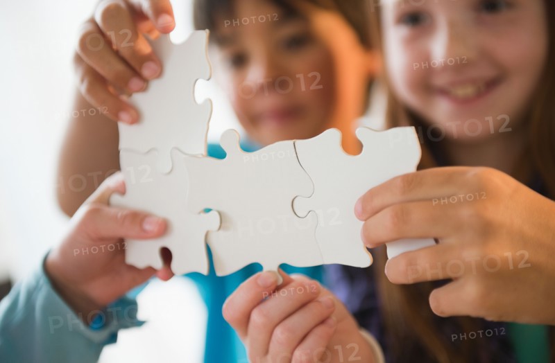 Close up of children's (8-9) hands holding jigsaw pieces