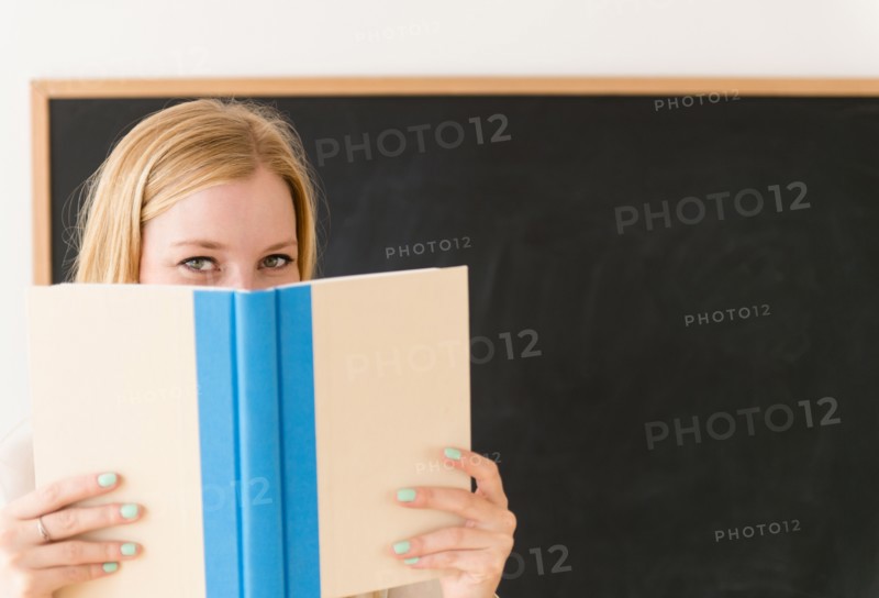 Portrait of woman shielding her face with book