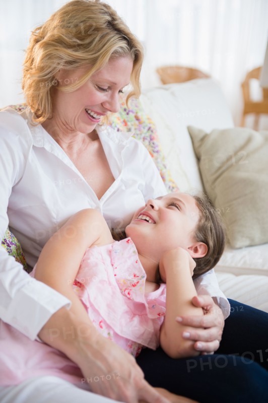 Mother and daughter (8-9 years) relaxing on sofa
