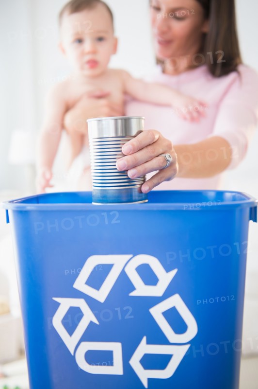 Mother and daughter (6-11 months) putting can into recycling bin