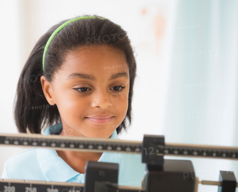 Girl (6-7 years) standing on weight scale