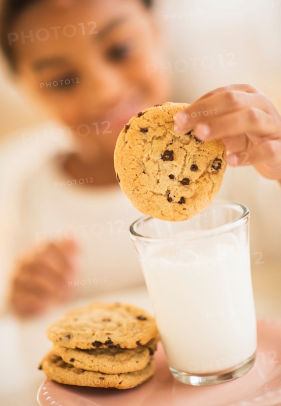 Girl (6-7) having cookie and milk