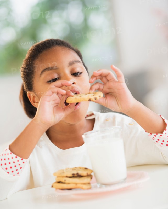 Girl (6-7) eating cookie