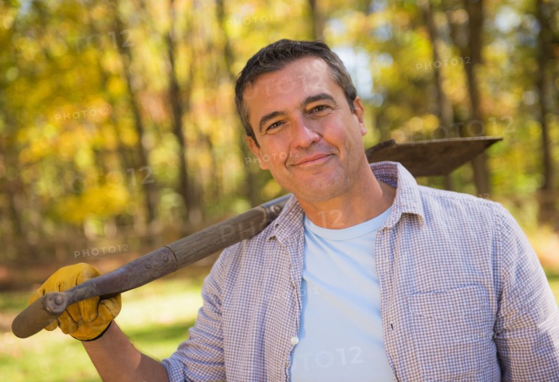 Portrait of smiling man holding shovel against his shoulder