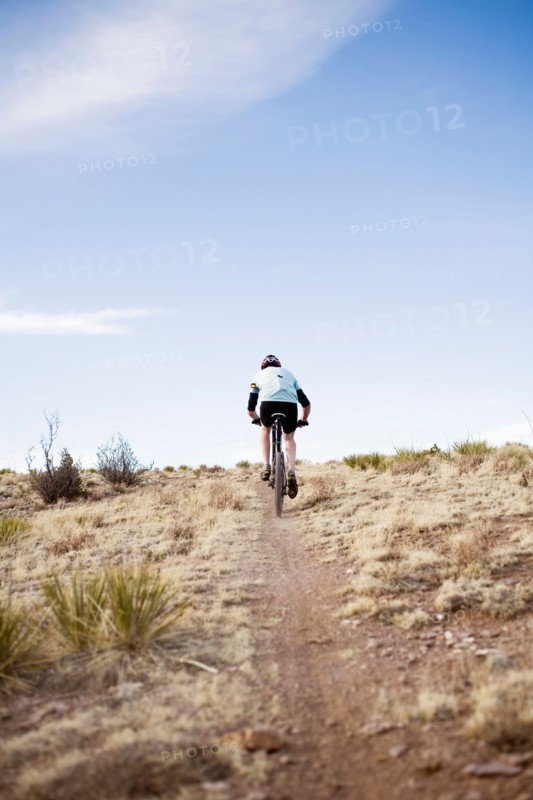 Rear view of man biking on trial
