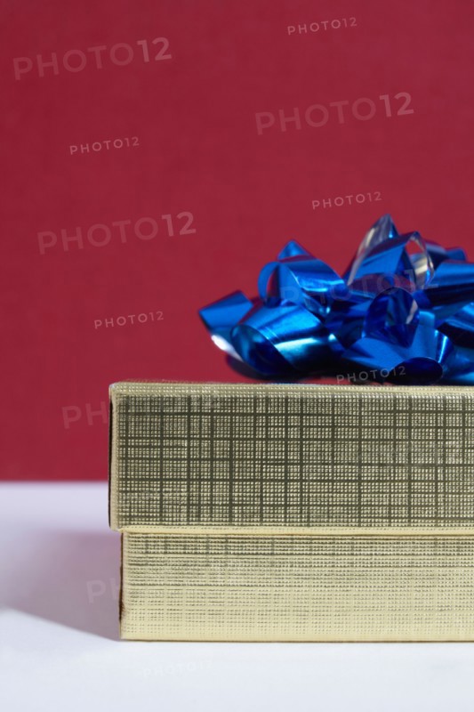 Studio shot of gift with blue bow on red background