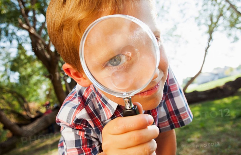 Little boy (6-7) looking through magnifying glass
