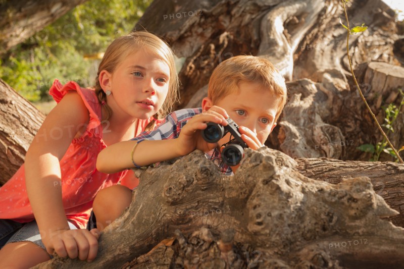 Little boy and little girl (6-7) looking at something in the distance with binoculars