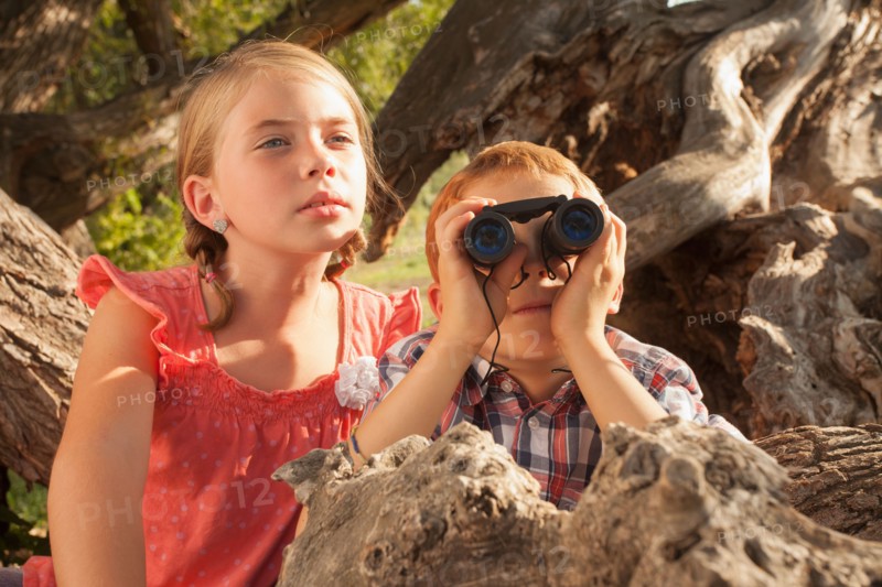 Little boy and little girl (6-7) looking at something in the distance with binoculars
