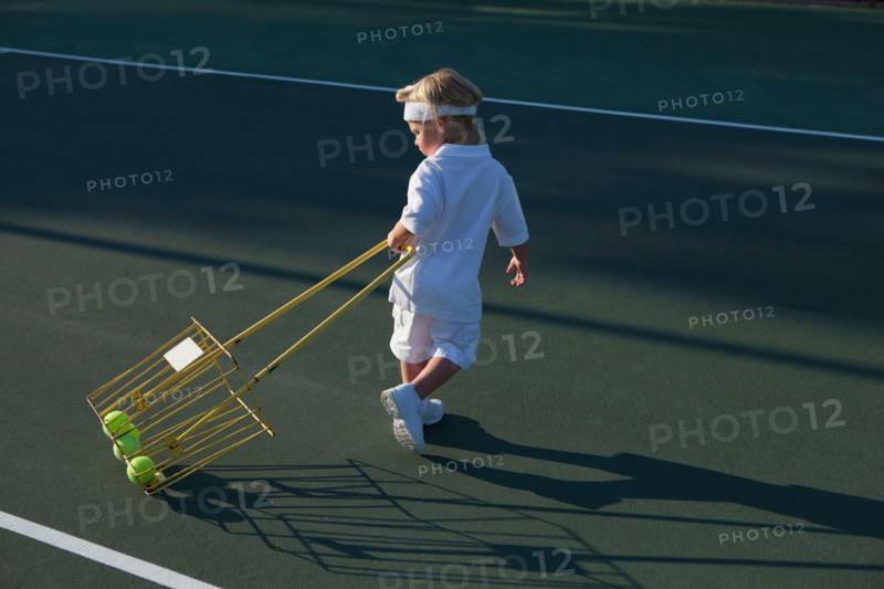 Boy (2-3) pulling basket with tennis balls