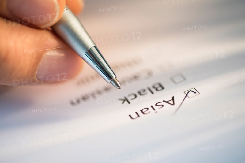Close-up of hand filling out form.