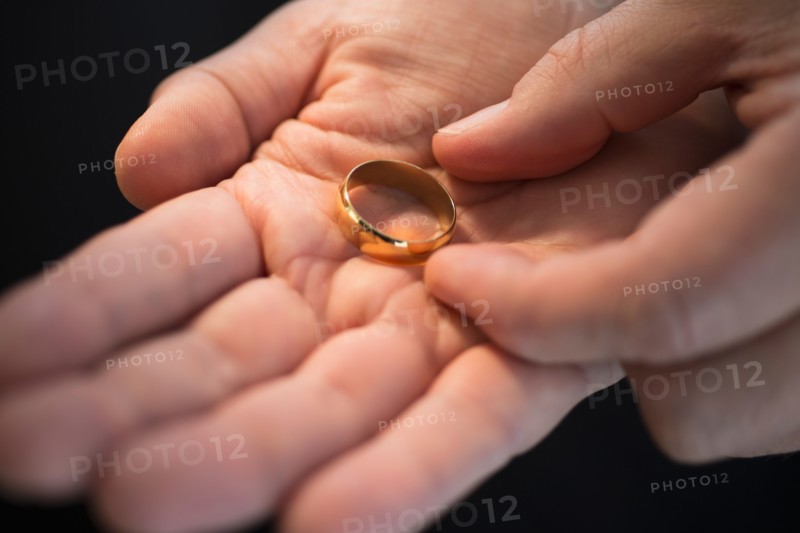 Hand holding wedding ring.