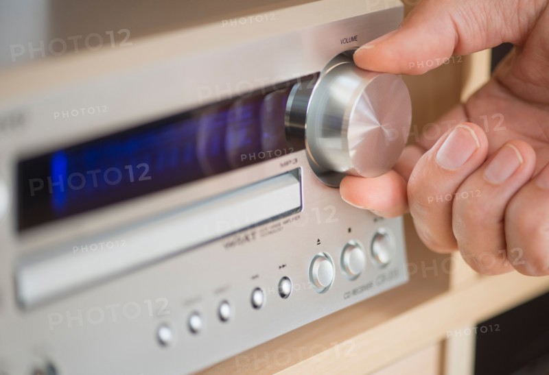 Close-up of hand adjusting audio system.