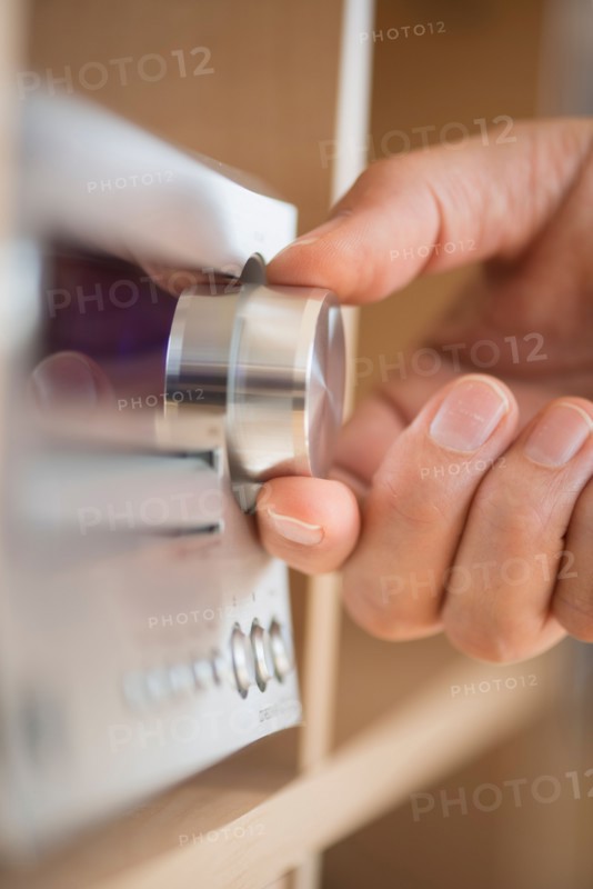 Close-up of hand adjusting audio system.