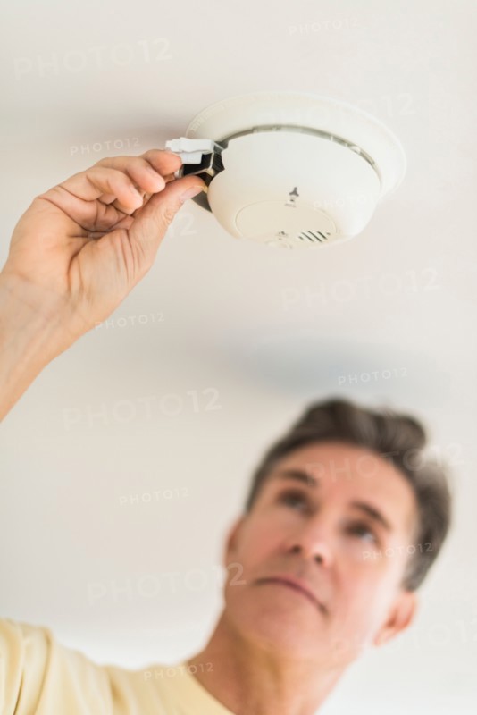 Man changing battery in smoke alarm.