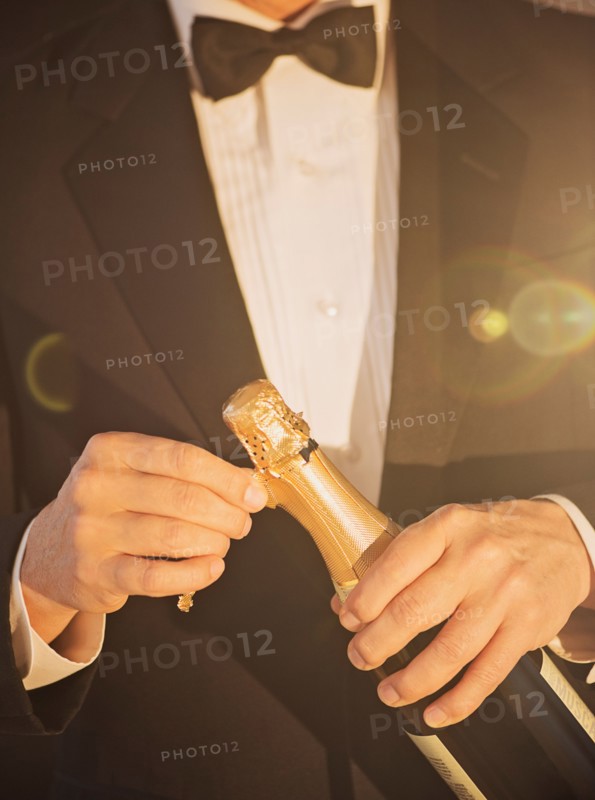 Elegant man opening champagne.