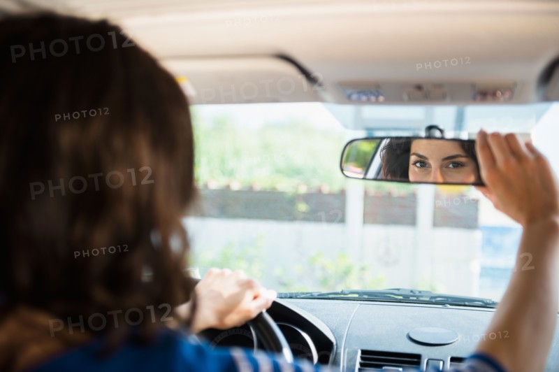 Woman adjusting rear view mirror in car. Photo: Jamie Grill
