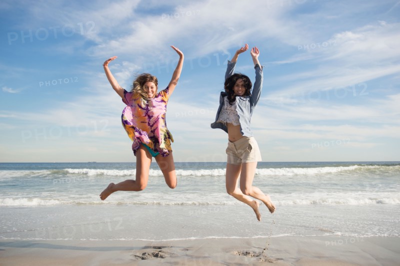 Two young women jumping on beach. Photo : Jamie Grill