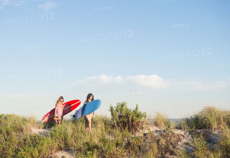Two female surfers walking on beach. Photo : Jamie Grill