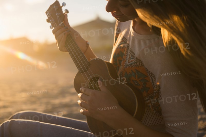 Woman playing ukulele at sunset. Photo: Jamie Grill