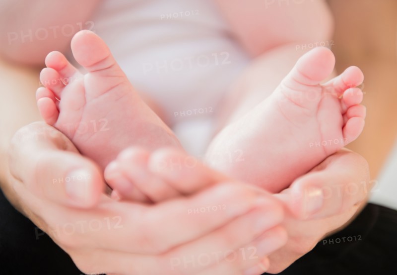 Mother holding feet of baby boy (2-5 months). Photo: Jamie Grill