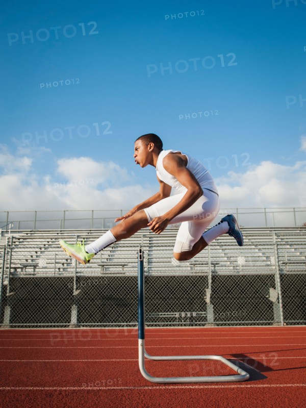 Boy (12-13) hurdling on running track. Photo: Erik Isakson