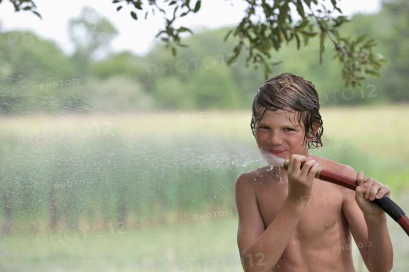 Boy (10-11) drinking from water hose in summer. Photo: pauline st.denis