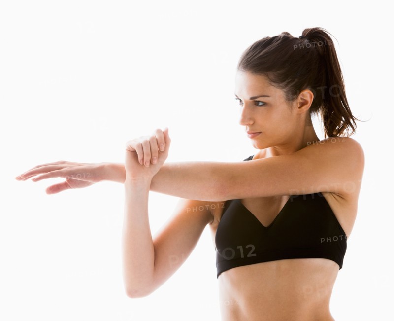 Young woman stretching, studio shot. Photo: Mike Kemp