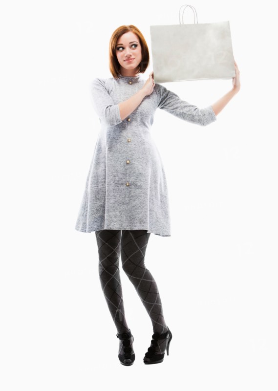 Young woman holding shopping bag, studio shot. Photo: Mike Kemp